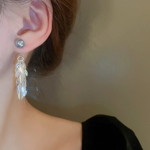Gros plan d'un mannequin portant des boucles d'oreilles feuilles à franges argentées