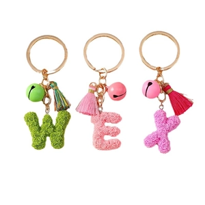Floral alphabet keychains with bells and tassels in pink and green on white background