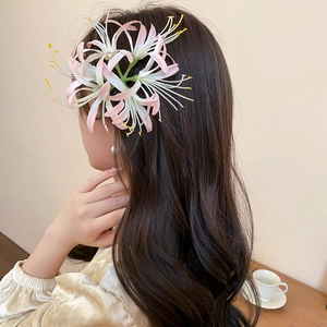 Detail view of pink and white gradient spider lily hair clip styled on wavy hair