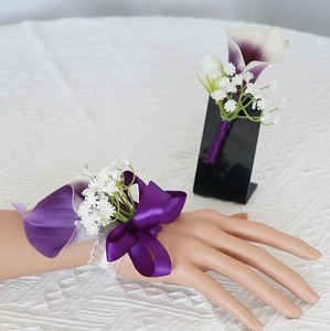Detail of dark purple calla lily wrist corsage and boutonniere with satin ribbon