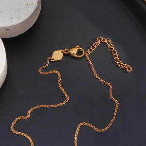 Close-up of gold necklace lobster clasp, extension chain and diamond-shaped tag