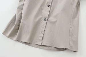 Detailaufnahme von grauem Baumwollhemd-Saum mit schwarzen Knöpfen und feinen Nähten