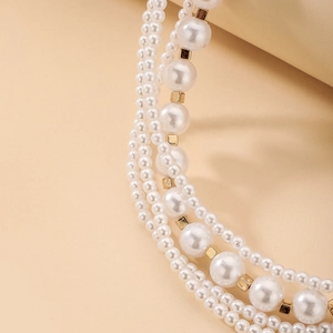 Detailed macro view of multi-layered pearl necklace with golden cube beads and high luster