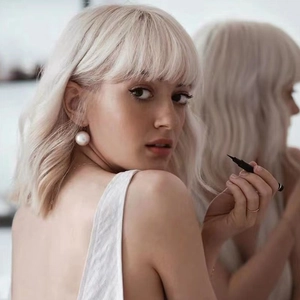 Model holding a black eyeliner pen in front of a mirror with professional lighting