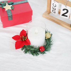Detail of LED candle set with red poinsettia wreath, golden baubles and pine needles