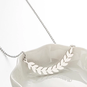 Silver stainless steel wheat ear leaf pendant necklace on white ceramic dish