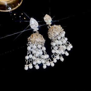 Gros plan de boucles d'oreilles pampilles en perles argentées avec strass sur noir