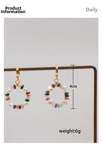 Detail of colorful beaded hoop earrings with pearls and gold hooks on T-bar display stand
