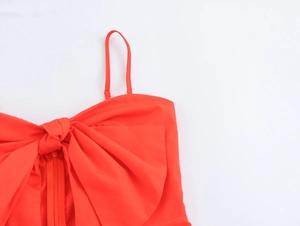 Close-up of red vacation dress featuring a large bow detail and delicate thin straps
