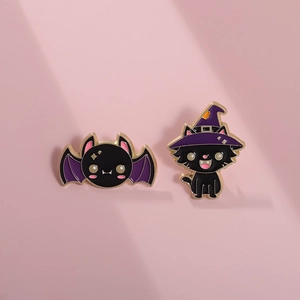 Detailed close-up of Halloween enamel pins featuring a black cat and purple bat on metal