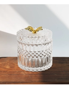 Detail of transparent glass storage jar with diamond pattern and gold butterfly handle