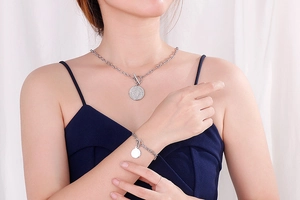 Detail of silver stainless steel coin pendant necklace and bracelet with toggle clasp