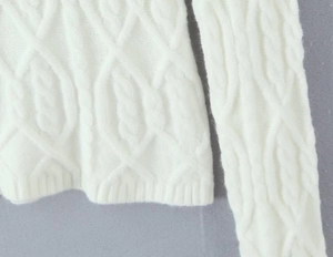 Detailed macro view of white cable knit texture and premium fiber on the sweater