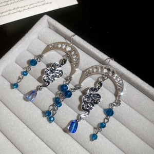Detail of silver crescent moon and snake earrings with blue crystal beads and tassels