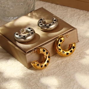 Hollow heart-shaped C-style earrings in gold and silver finish on a jewelry box