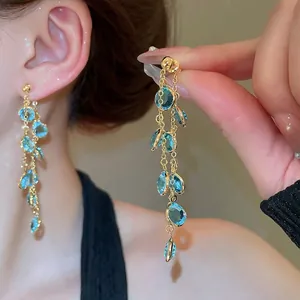 Eleganti orecchini a nappa placcati oro 18k con perline sfaccettate azzurre su una modella