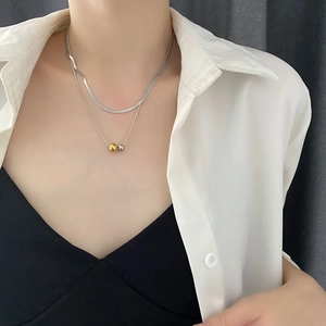 Double-layered titanium steel necklace with gold and silver ball pendants on a flat snake chain