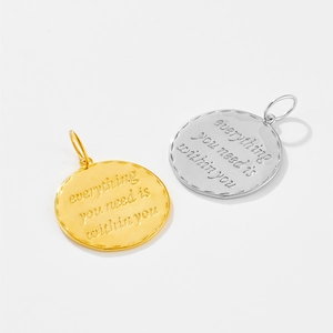 Close-up of gold and silver S925 sterling silver pendants with motivational engraving