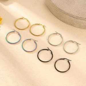 Detail view of four pairs of large hoop earrings in gold, rainbow, silver and black steel
