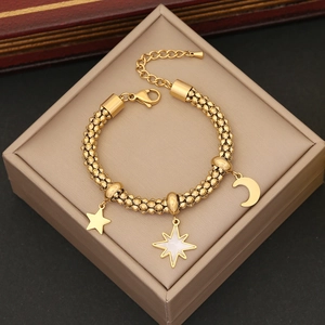 Detail of gold beaded bracelet featuring star and moon charms on a jewelry box