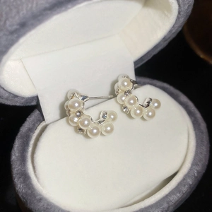 Detail of silver drop earrings with pearls and rhinestones in a velvet jewelry box