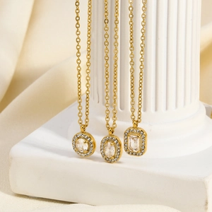 Trois colliers dorés en acier inoxydable avec pendentifs zircon sur fond de soie