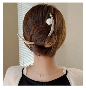Detail of crescent moon hair pin with pearl and engraved pattern in elegant updo