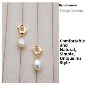 Close-up of French vintage gold geometric earrings with white baroque pearl drops