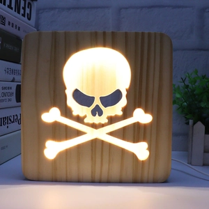 Close-up of square 3D wooden night light with glowing skull and crossbones cutout