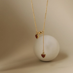 Elegant gold necklace with dual deep red heart pendants in minimalist French style