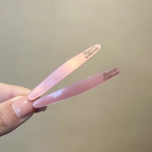 Pink Korean style duckbill hair clips with gold lettering held in hand