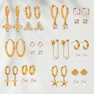 Gold stainless steel earring set with pearls, zircons, and cross charms on gray background