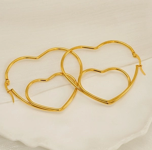 Vue macro de boucles d'oreilles créoles coeur double couche en acier inoxydable doré poli