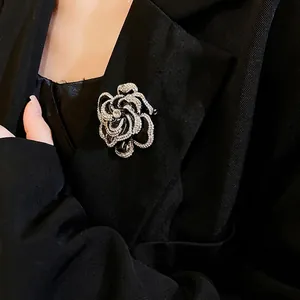 Elegant black camellia brooch with rhinestones worn on a black blazer lapel