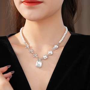 Close-up of elegant silver floral pendant necklace with white pearls and zircons on model