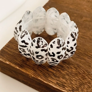 Macro shot of black and white leopard print acrylic link bracelet on a wooden base