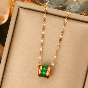 Detail of rose gold cylinder pendant with emerald-cut green stones in jewelry box