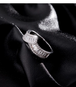 Macro view of sterling silver wide ring with shimmering diamonds on black silk background