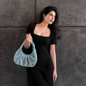 Détail d'un sac à main bleu clair plissé avec une robe en maille côtelée noire