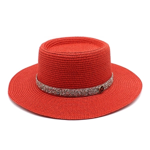 Red flat top straw boater hat with shimmering rhinestone band and golden M logo