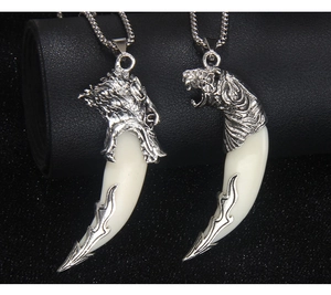 Detail of wolf head and tooth pendants with metal chains on a black background