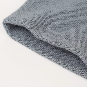 Makro-Detailaufnahme der weichen grauen Stricktextur einer Kinder-Wintermütze aus Wolle.