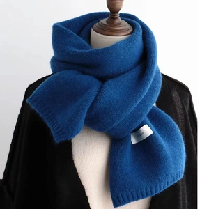 Detail of blue knitted scarf on neck with soft texture and FENING woven label
