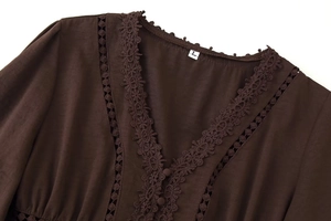 Detailansicht des tiefen V-Ausschnitts mit Spitzenbesatz und Knöpfen am braunen Kleid