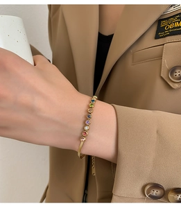 Detail of gold snake chain bracelet with multi-colored gemstones on a wrist