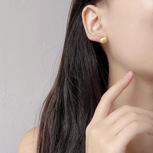Primo piano di orecchini a cerchio dorati spazzolati minimalisti indossati da una modella