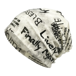 Off-white distressed knit beanie with black graffiti letters and ripped details