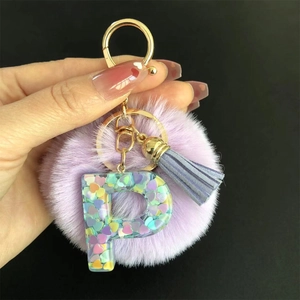 Détail du porte-clés lettre P en résine violette avec paillettes, pompon et frange