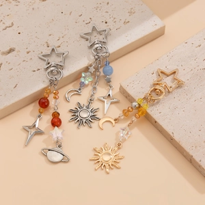 Celestial keychain with sun, moon, and stars charms on textured stone background