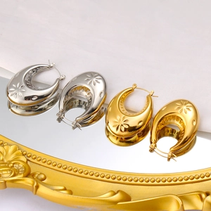 Detail von gold- und silbernen C-förmigen Ohrringen mit Sternen-Reliefmuster